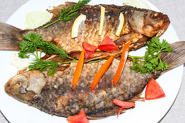 Image showing Fresh crucian river fish fried in lemon juice and fresh herbs.