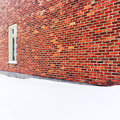 Image showing Empty space covered by snow near a brick wall