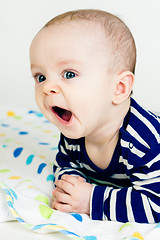 Image showing cute baby in striped clothes lying down on a blanket