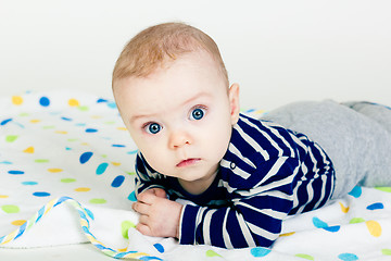 Image showing cute baby in striped clothes lying down on a blanket