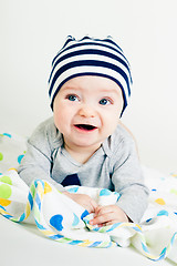 Image showing cute baby in striped hat lying down on a blanket