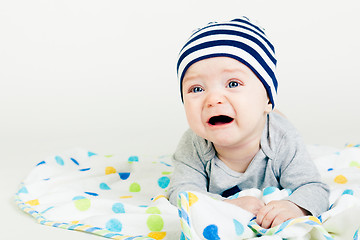 Image showing cute baby in striped hat lying down on a blanket