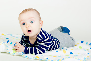 Image showing cute baby in striped clothes lying down on a blanket