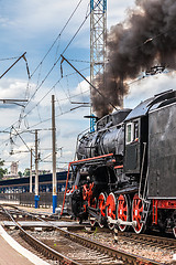 Image showing Old steam train is leaving a station