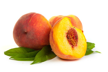 Image showing Three perfect, ripe peaches with a half  and slices isolated on 