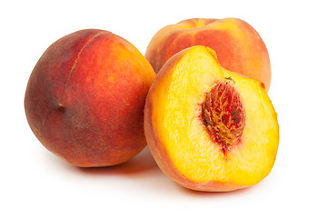 Image showing Three perfect, ripe peaches with a half  and slices isolated on 