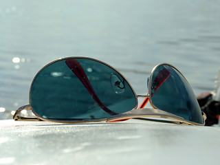 Image showing The sunglasses laying on a white surface on a background of wate