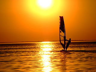 Image showing Silhouette of a windsurfer on waves of a gulf on a sunset