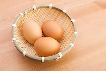 Image showing Egg in basket over wooden background