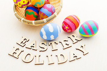 Image showing Colourful easter egg in wicker basket with wooden text