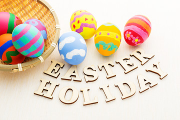 Image showing Colourful easter egg in basket with wooden text 