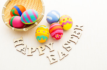 Image showing Colourful easter egg in basket with wooden text