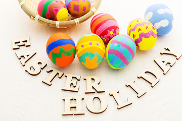 Image showing Colourful easter egg in basket with wooden text