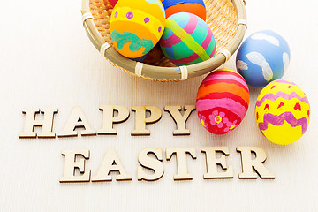 Image showing Colourful painted easter egg in basket with wooden text 