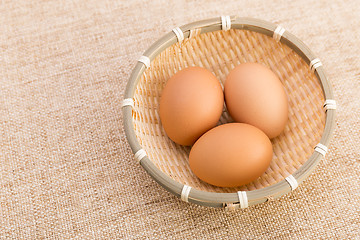 Image showing Brown egg in basket over linen background