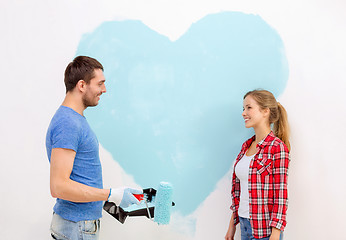 Image showing smiling couple painting big heart on wall