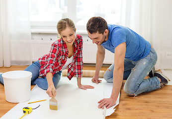 Image showing smiling couple smearing wallpaper with glue