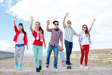 Image showing group of smiling teenagers waving hands