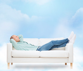 Image showing smiling man lying on sofa