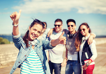 Image showing teenage girl with headphones and friends outside