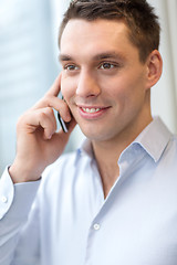 Image showing smiling businessman with smartphone in office