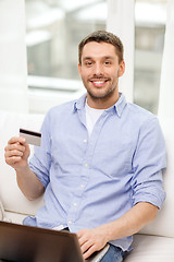 Image showing smiling man working with laptop and credit card