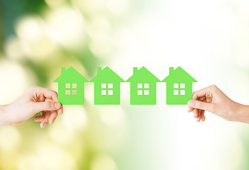 Image showing man and woman hands with many green paper houses