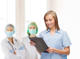 Image showing smiling female doctor or nurse with clipboard