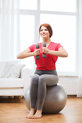 Image showing smiling redhead girl exercising with fitness ball