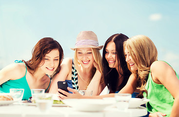 Image showing girls looking at smartphone in cafe on the beach