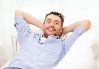 Image showing smiling man lying on sofa at home