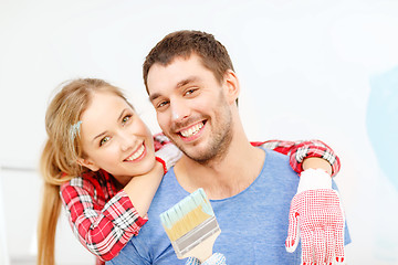 Image showing smiling couple covered with paint with paint brush