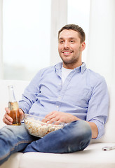Image showing smiling man with beer and popcorn at home