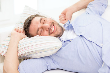 Image showing smiling young man lying on sofa at home