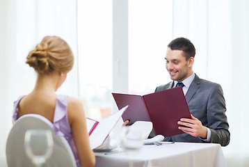 Image showing smiling young man looking at menu at restaurant