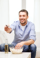 Image showing smiling man with tv remote control at home