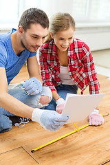 Image showing smiling couple measuring wood flooring