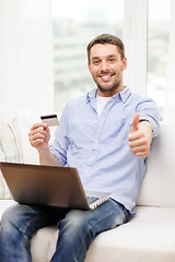 Image showing smiling man working with laptop and credit card