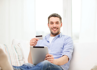 Image showing smiling man working with tablet pc at home