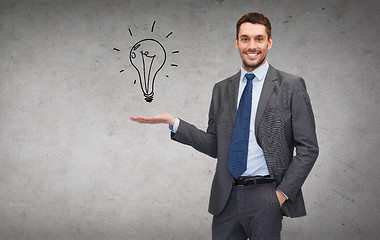 Image showing man showing light bulb on the palm of his hand