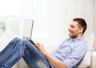 Image showing smiling man working with laptop at home