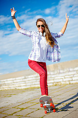 Image showing smiling teenage girl riding skate outside