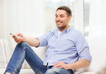 Image showing smiling man with tv remote control at home