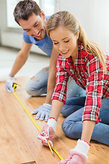 Image showing smiling couple measuring wood flooring