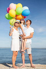 Image showing happy family with colorful balloons at seaside