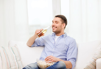 Image showing smiling man with beer and popcorn at home