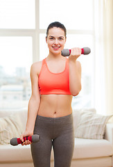 Image showing smiling teenage girl exercising with dumbbells