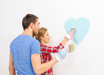 Image showing smiling couple painting small heart on wall