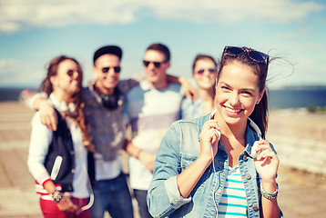 Image showing teenage girl with headphones and friends outside