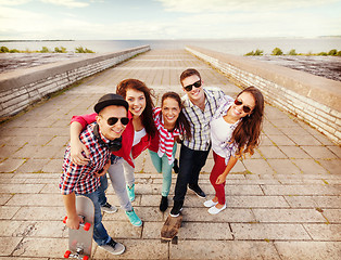 Image showing smiling teenagers with skates outside